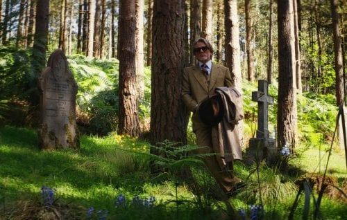 Daniel Craig as detective Benoit Blanc, standing in a green cemetery.